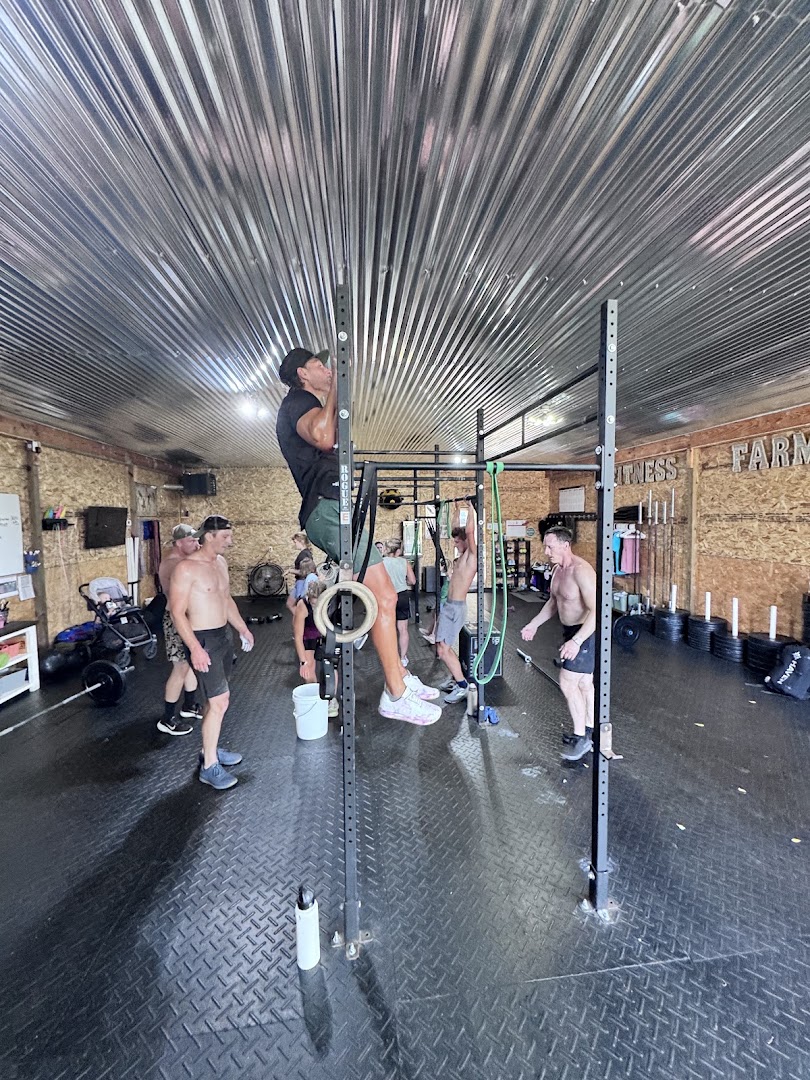 Athlete on the pull up bar with the FITNESS FARM wall lettering behind