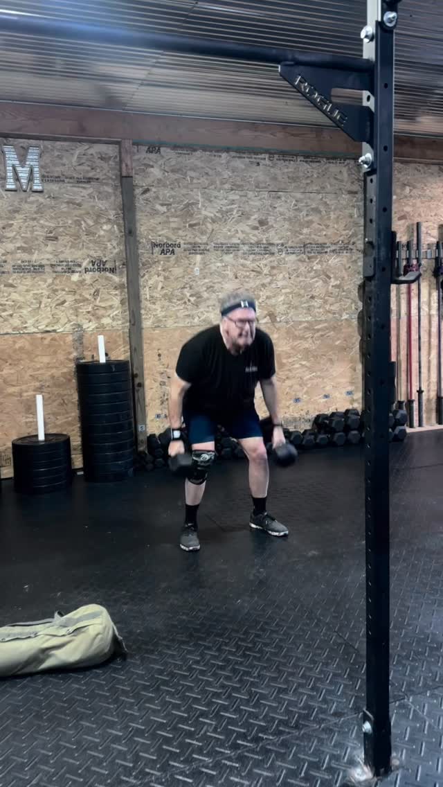 An older member working with dumbbells in the barn