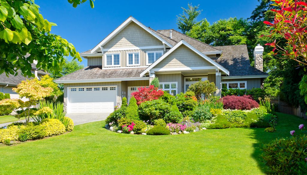 Freshly landscaped home with layered beds, shrubs and a striped lawn